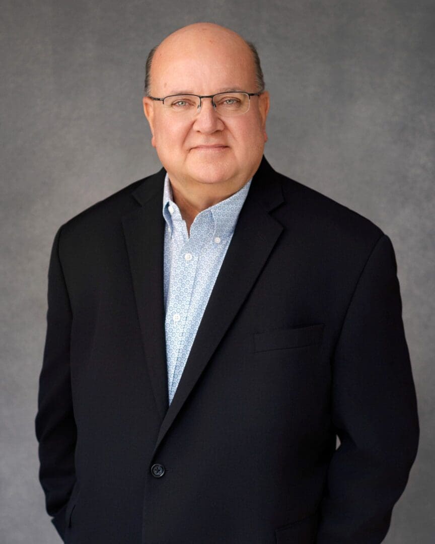 Professional portrait of a man in a suit jacket and glasses.