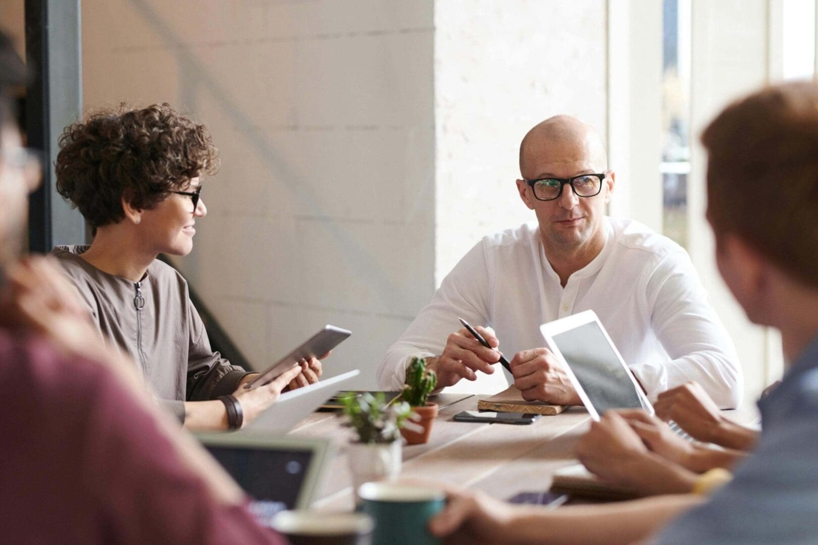 People collaborating in a bright office with digital devices and coffee.