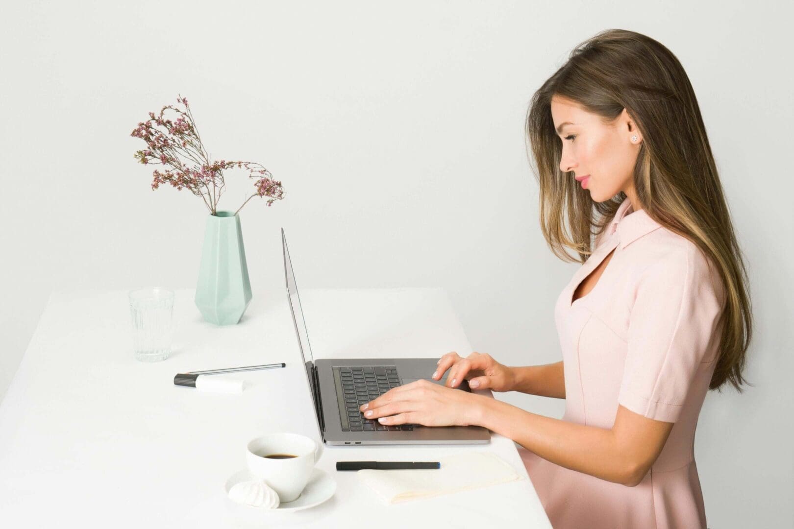 Woman working on a laptop at a clean, minimalistic desk.