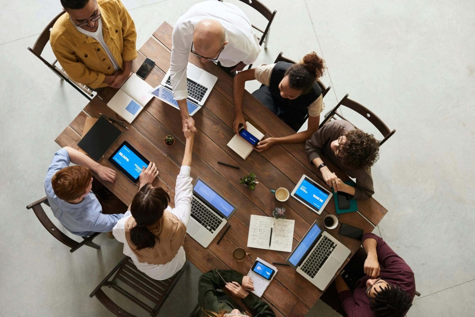 Team collaborating around a table with laptops and documents in a modern office.