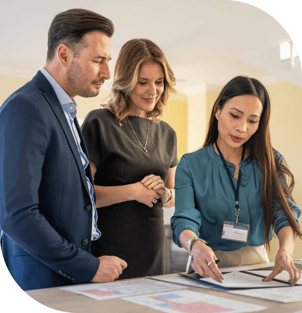 Three professionals discussing documents in a bright office.