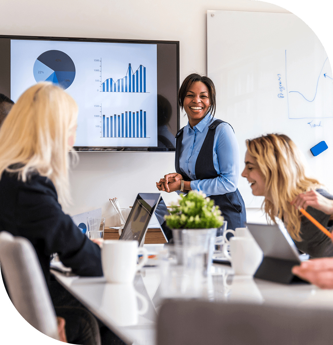 A woman presents data to colleagues in a modern office meeting.