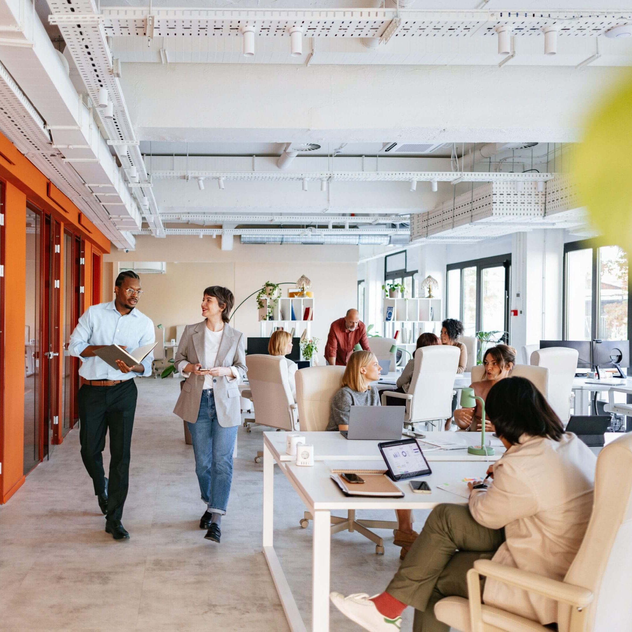 Modern office space bustling with employees working and collaborating.